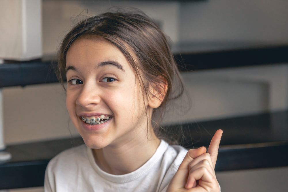 a little girl is wearing orthodontics and smiling